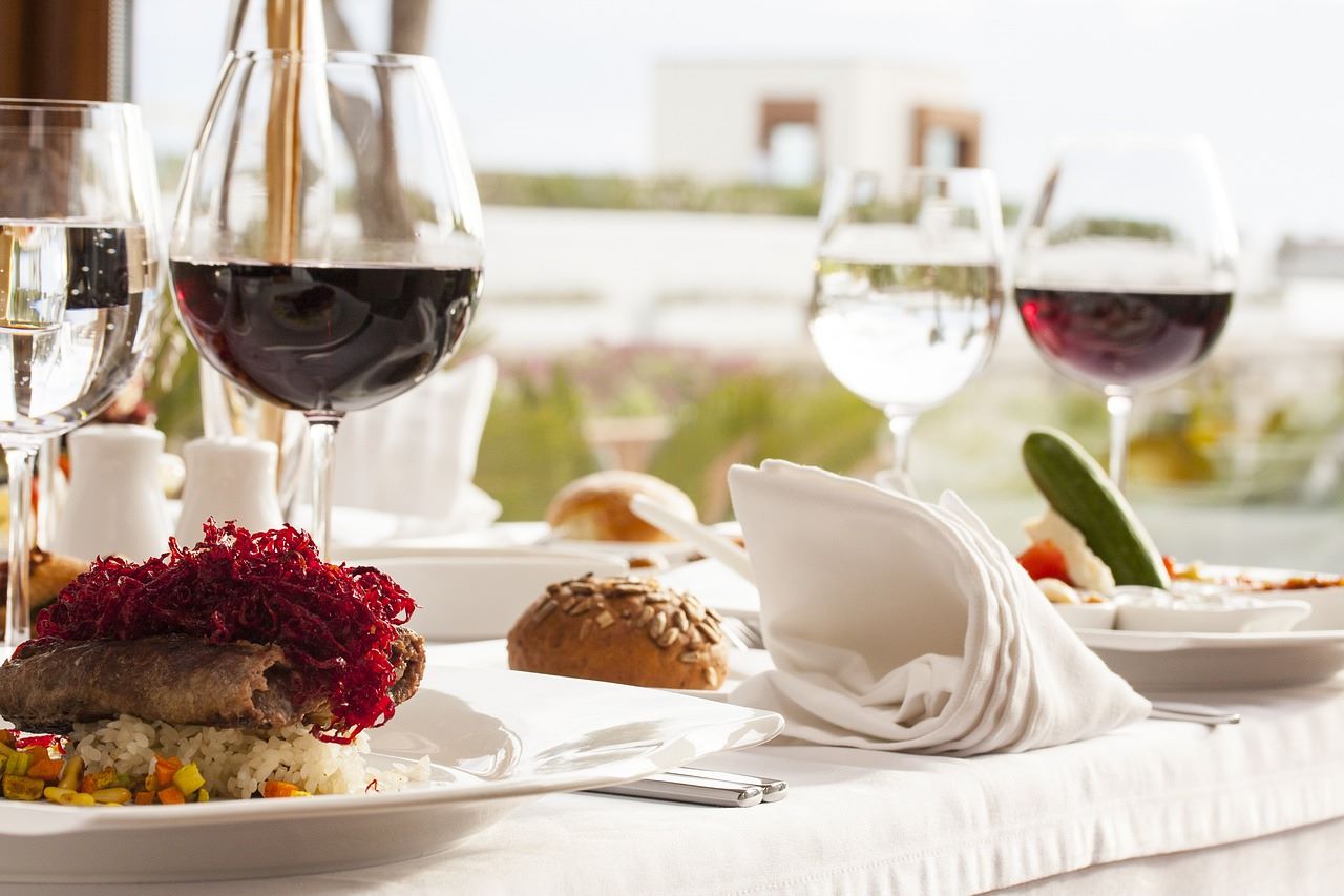 ブドウ畑をバックに、テーブルに置かれた料理とワインが注がれているグラス
